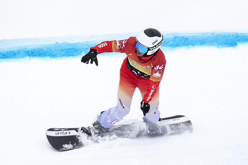 Ein Snowboarder in einem roten Trikot, mit weißem Helm und Brille fährt auf einer verschneiten Piste und wirbelt bei einer Kurve Pulverschnee auf. Eine blaue Linie markiert den Kurs auf dem Schnee neben ihnen.