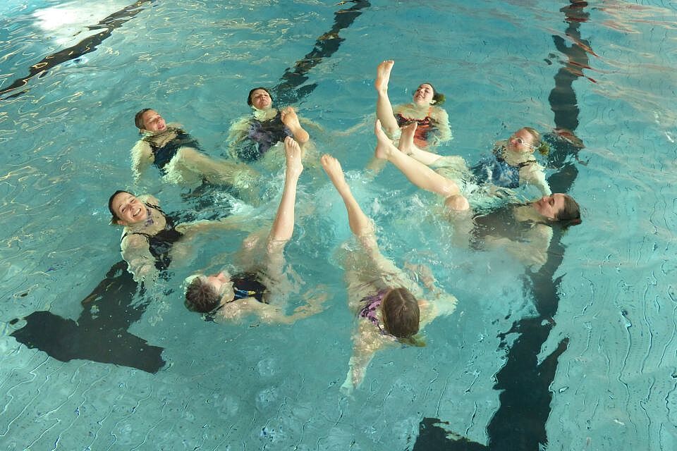 Teilnehmer bilden einen Kreis und strecken ein Bein aus dem Wasser