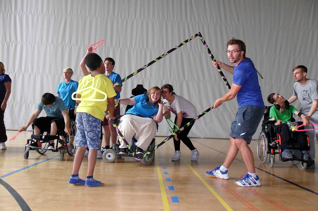Spielende Kinder und Jugendliche mit unterschiedlichen Behinderungsformen vergnügen sich in der Turnhalle 