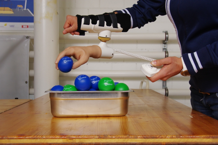 Hand mit montierter Roboterhand greift nach Ball