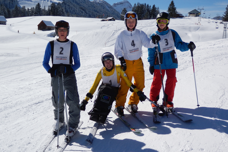 Skitalente sitzend im Skibob und stehend mit Skis auf der Piste